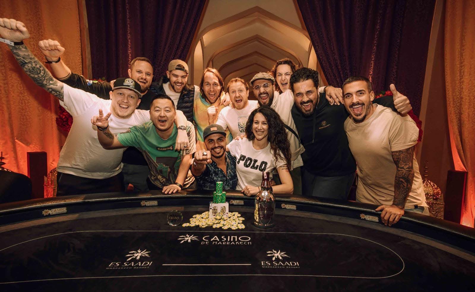 Playbook student Dinesh Alt celebrating a tournament win with friends, chips and a trophy